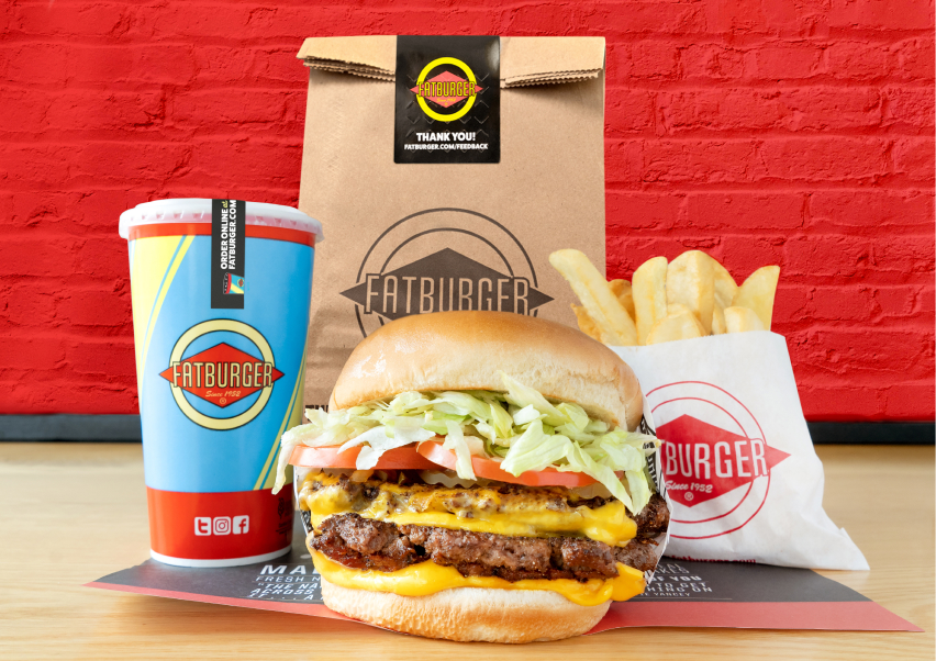 a photo of a fatburger, fries, drink, and to go bag
